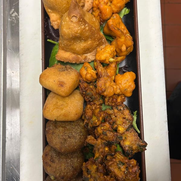 A platter of various Indian appetizers, including samosas, pakoras, and other fried snacks.